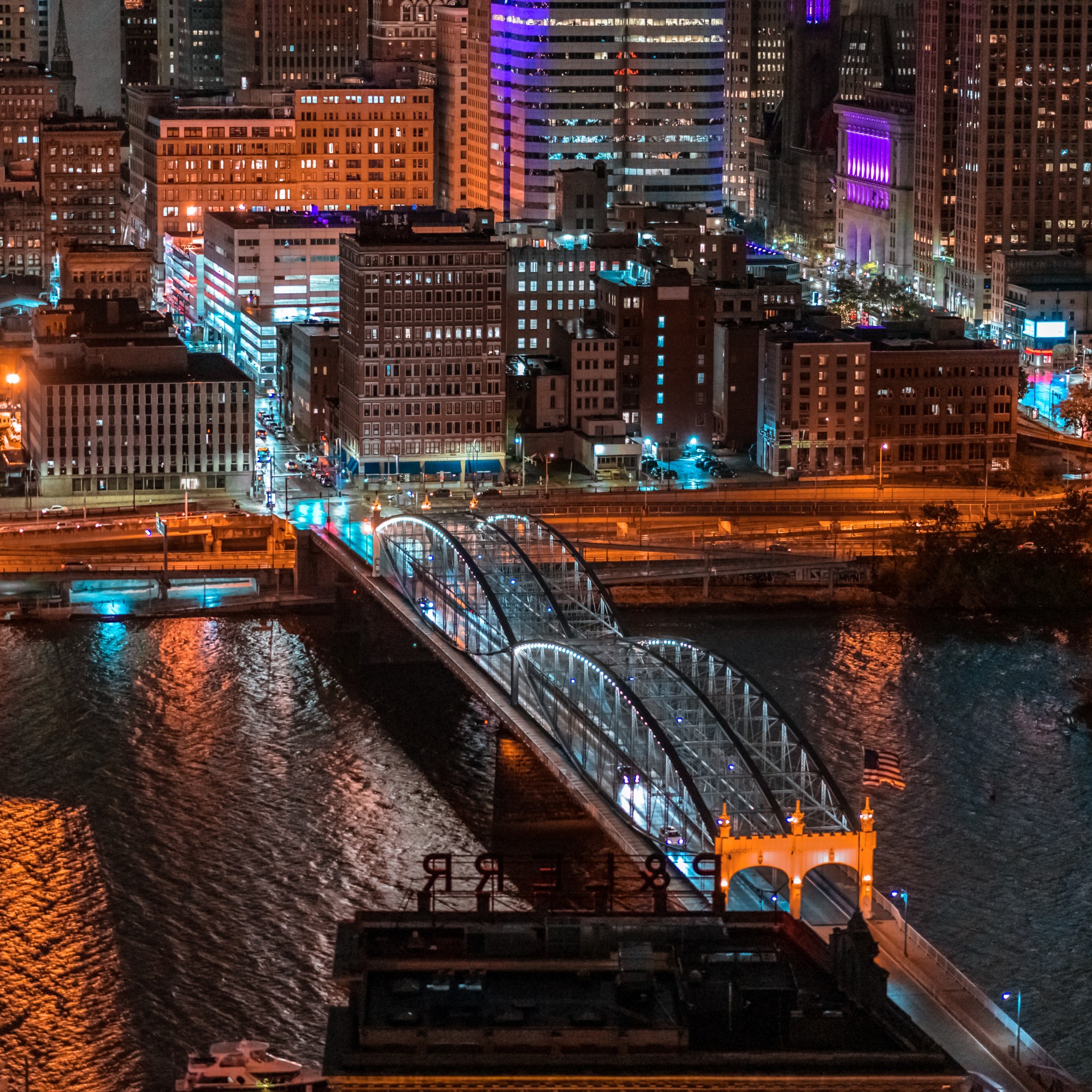 Overhead photo of a bridge over water leading to a city at night